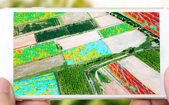Hands holding a smartphone with aerial image of landscape	