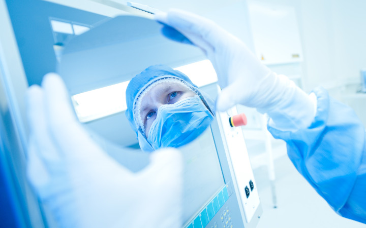 Scientist holding a circular mirror looking at their reflection