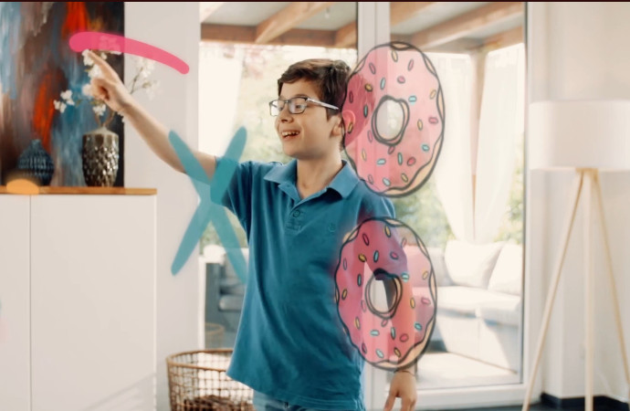 Small boy standing in front of an augmented reality game in a home