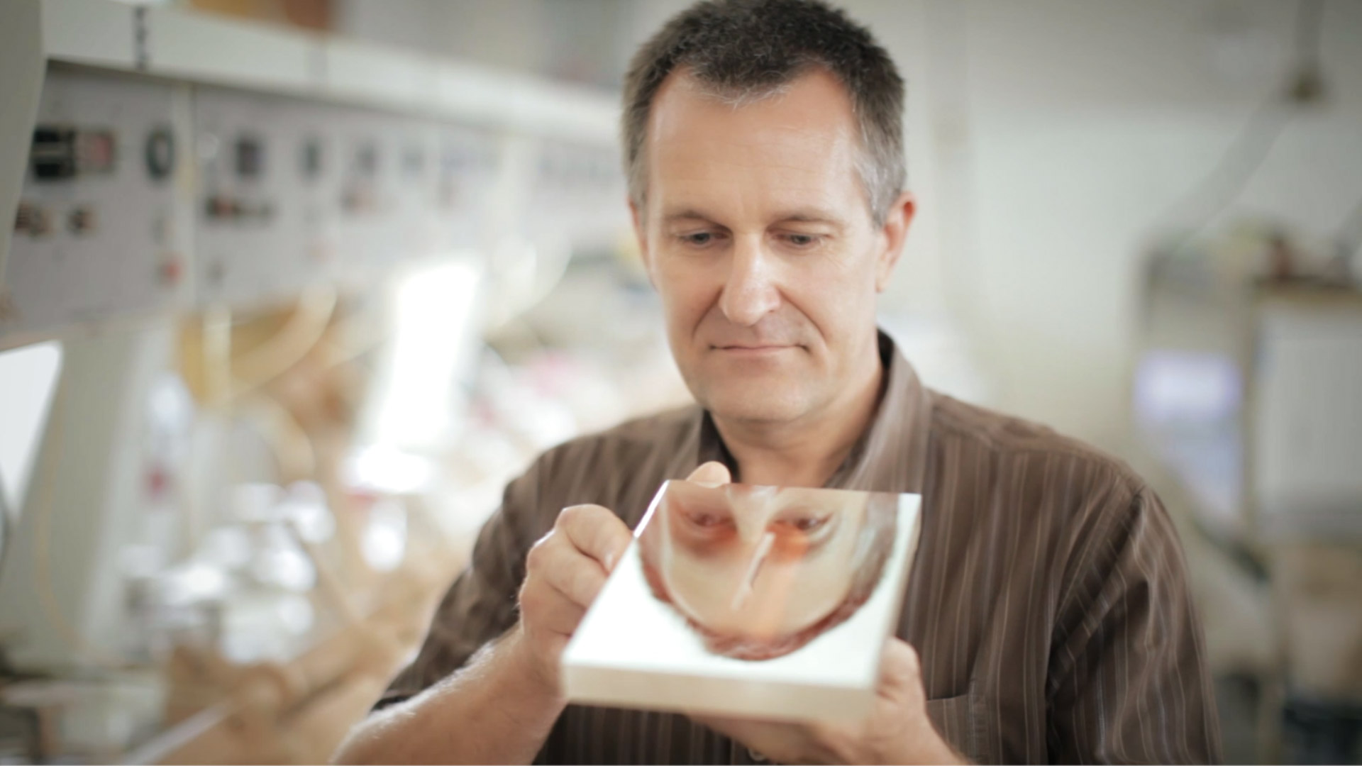 Male glass expert looking at a square optical mirror in a laboratory